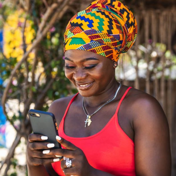 Ghana woman with african colorful headdress standing in the village keta with mobile phone